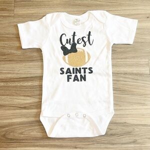 Laughing Giraffe Cutest Saints Fan black/gold glitter baby bodysuit